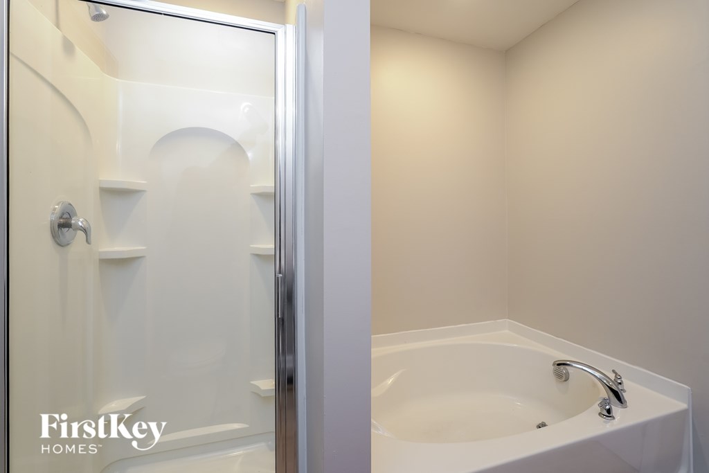 A white bathroom with a glass shower door and a white bathtub.