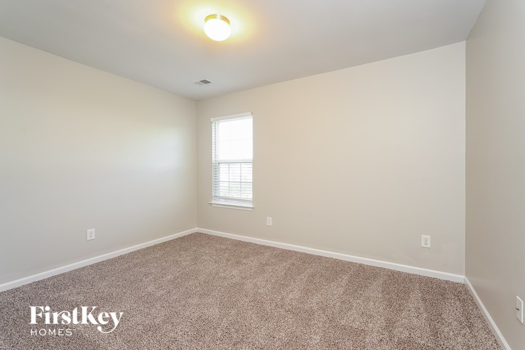 A room with a carpeted floor and a window with blinds.
