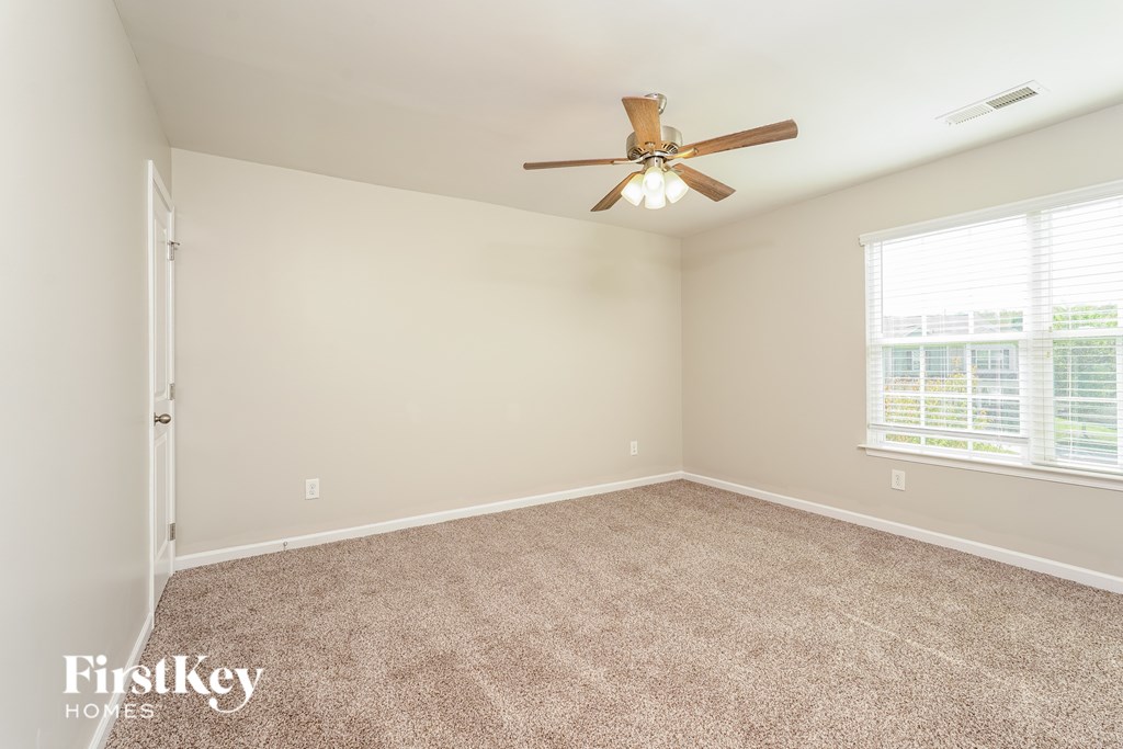 A room with a ceiling fan and a window with blinds.