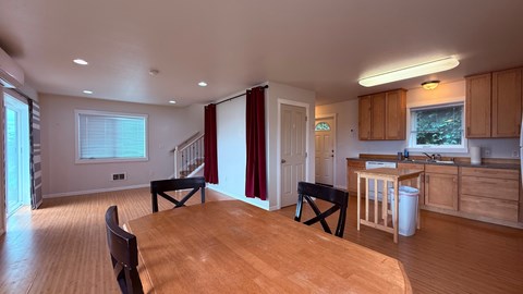 A kitchen with wooden floors and a dining table with chairs.