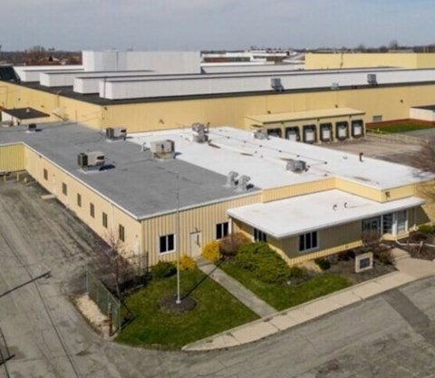 A large industrial building with a yellow and white exterior and a grey roof.