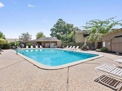 A swimming pool surrounded by a concrete patio and a white fence.