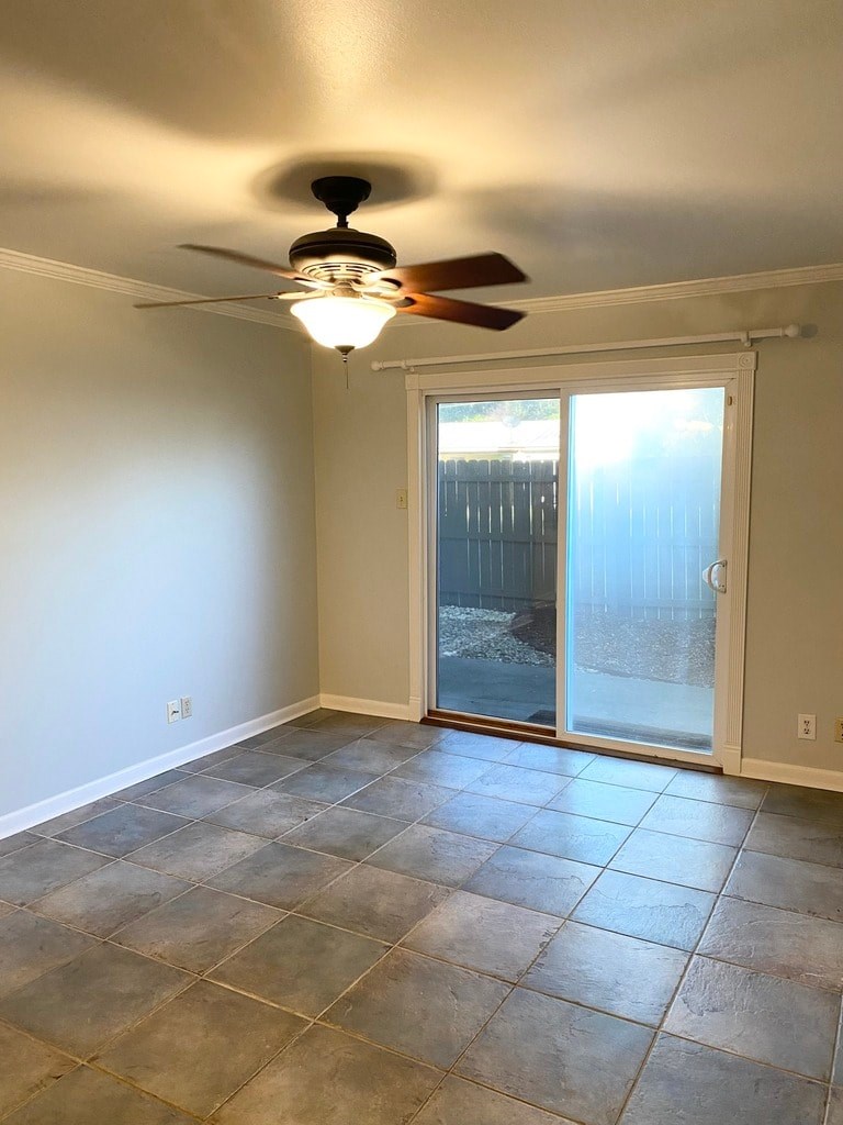 A room with a ceiling fan and sliding glass doors.