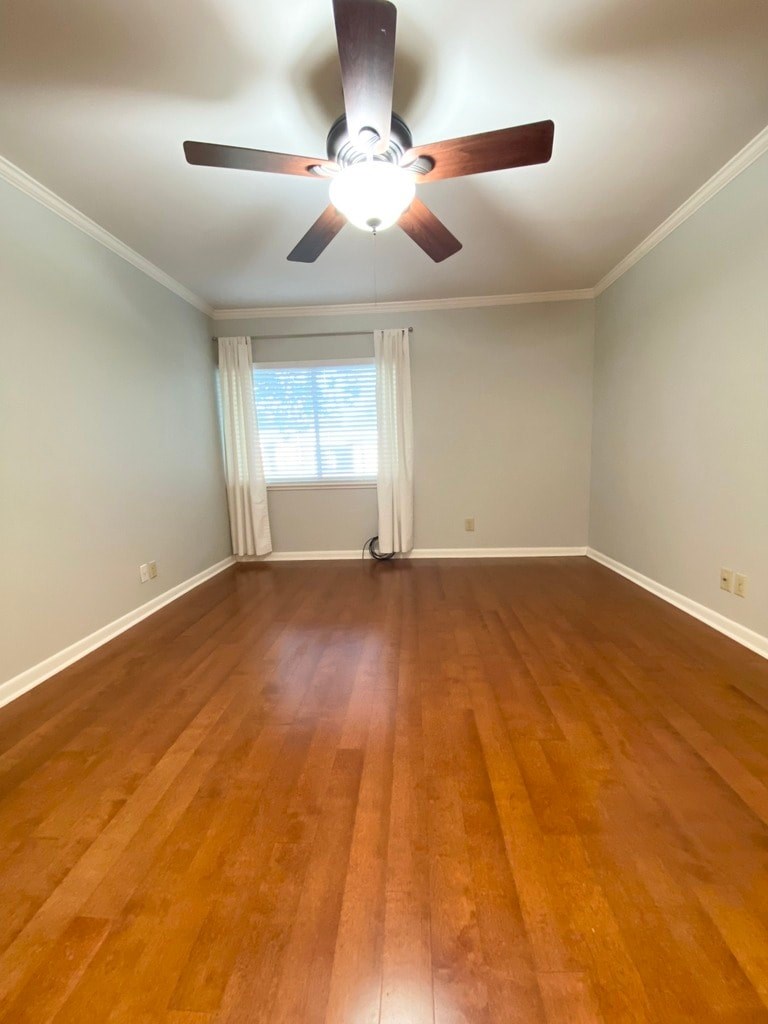 A room with a ceiling fan and wooden flooring.