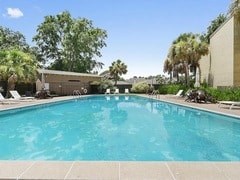 A large swimming pool surrounded by trees and a building.