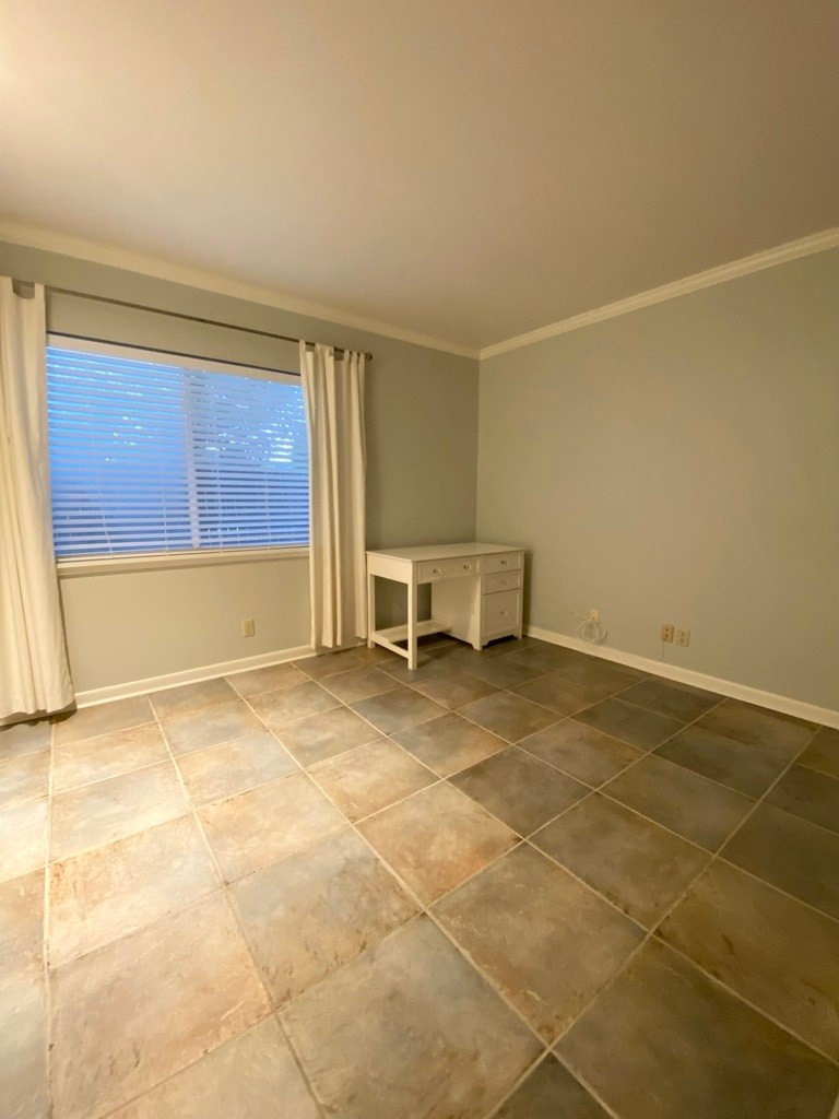 A room with a tile floor and a desk with a chair.