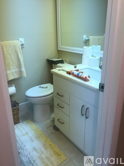 A bathroom with a toilet, sink, and mirror.