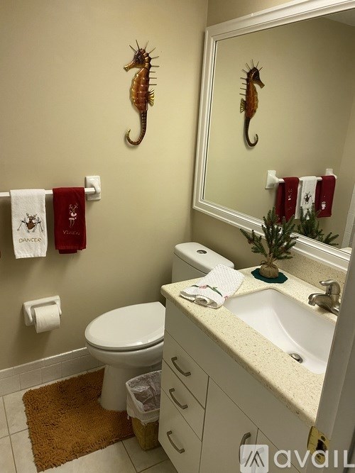 A bathroom with a toilet, sink, and two seahorse wall decorations.