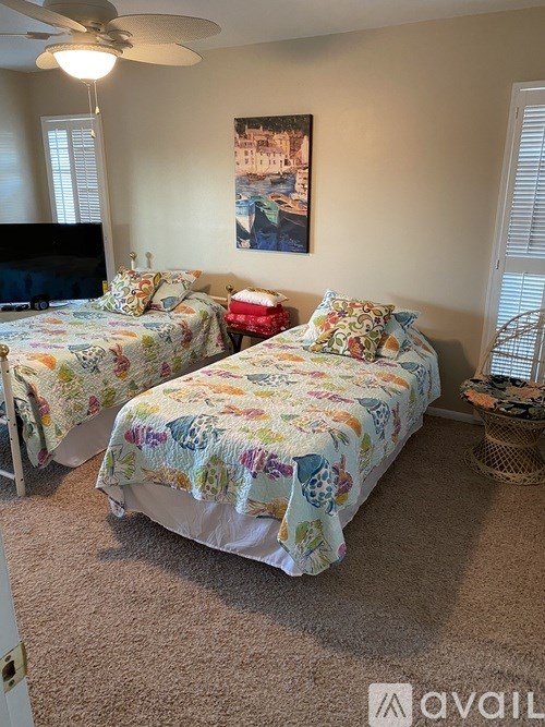 Two twin beds with floral bedspreads in a room with a ceiling fan.