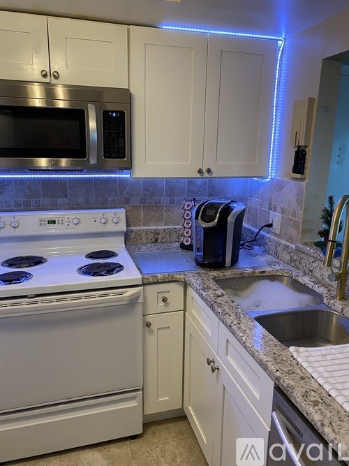 A kitchen with a white stove top oven and white cabinets.