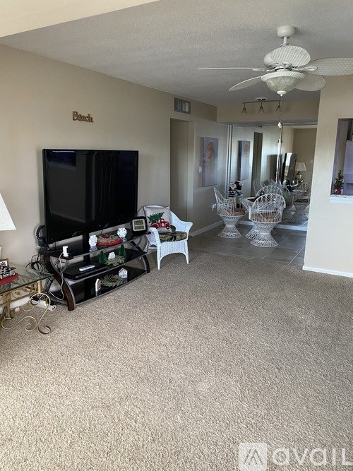 A living room with a flat screen TV and a glass coffee table.
