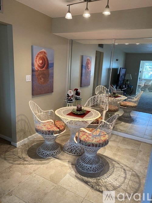 A dining room with a table set for four and a painting on the wall.