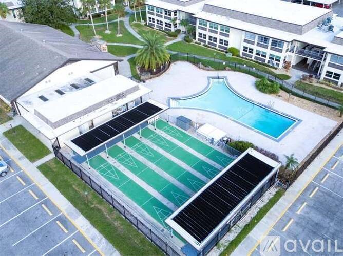 A swimming pool surrounded by a fence and a building with solar panels on the roof.