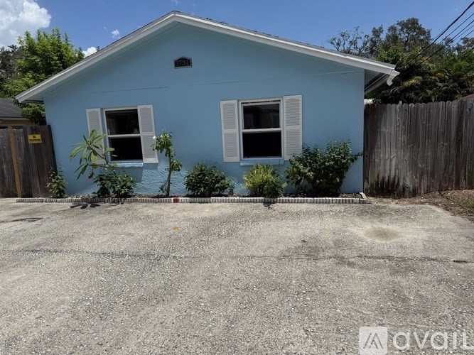 A blue house with a gravel driveway in front.