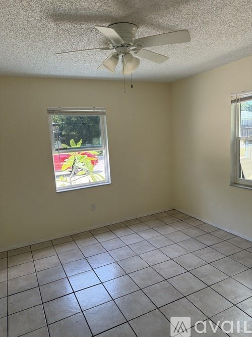 A room with a ceiling fan and two windows.
