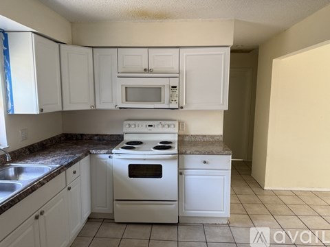 A kitchen with white cabinets and a white stove top oven.