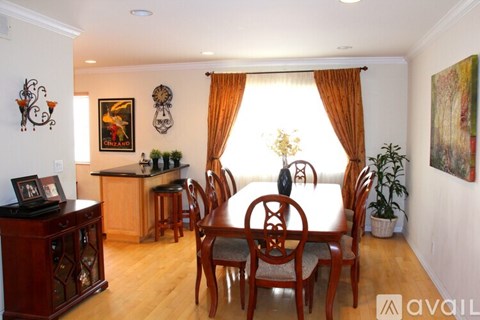 A dining room with a table set for two and a kitchen area in the background.