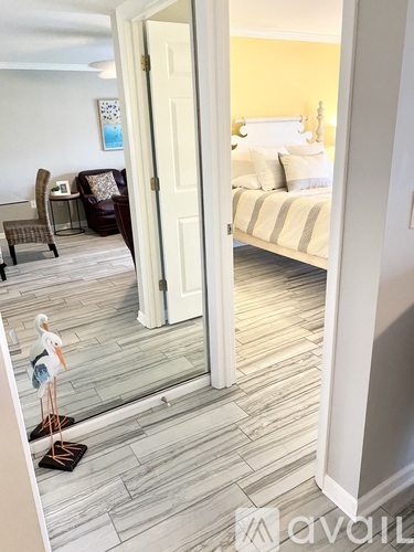 A bedroom with a bed and a chair is visible through an open door.