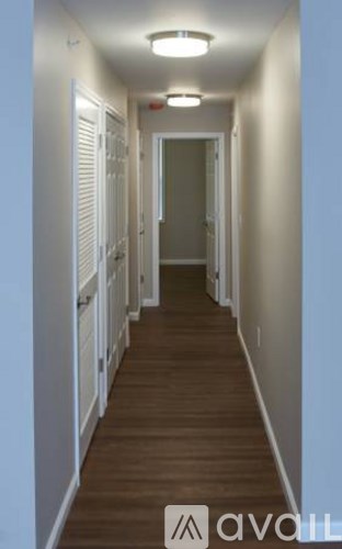 A long hallway with white walls and wood floors.