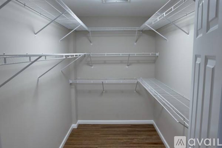 Empty walk-in closet with white shelves and wooden floor.