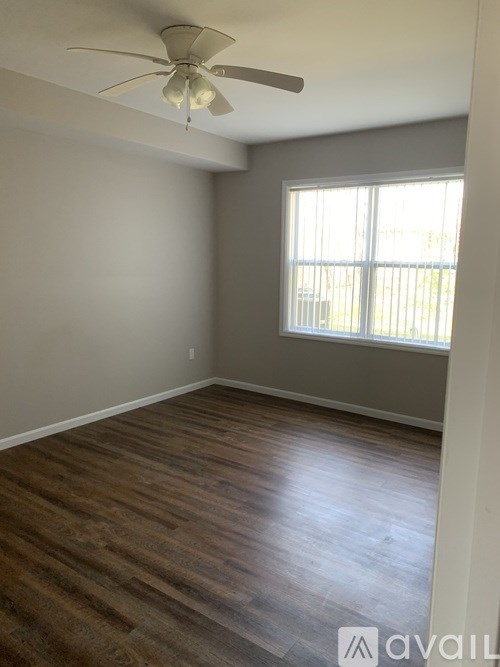 A room with a ceiling fan and wooden flooring.