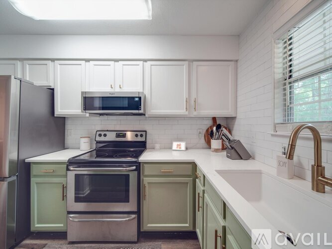 A kitchen with white cabinets and greenish-grey appliances.