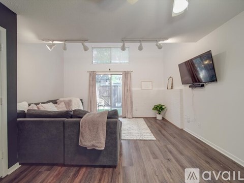 A living room with a grey couch and a flat screen TV mounted on the wall.