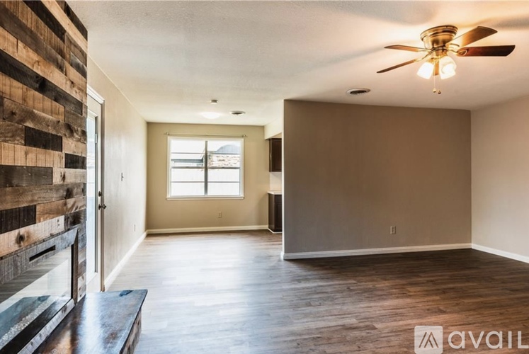A spacious room with wooden floors and a ceiling fan.
