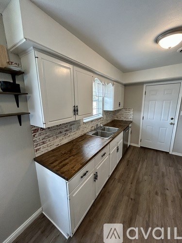 A kitchen with white cabinets and a wooden countertop.
