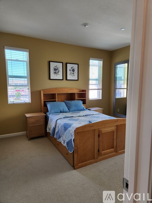 A bedroom with a bed, nightstand, and two framed pictures on the wall.