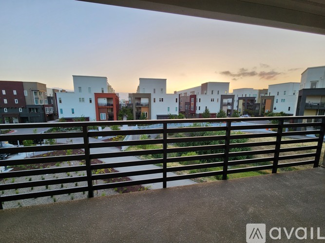 A balcony overlooks a row of modern buildings at dusk.
