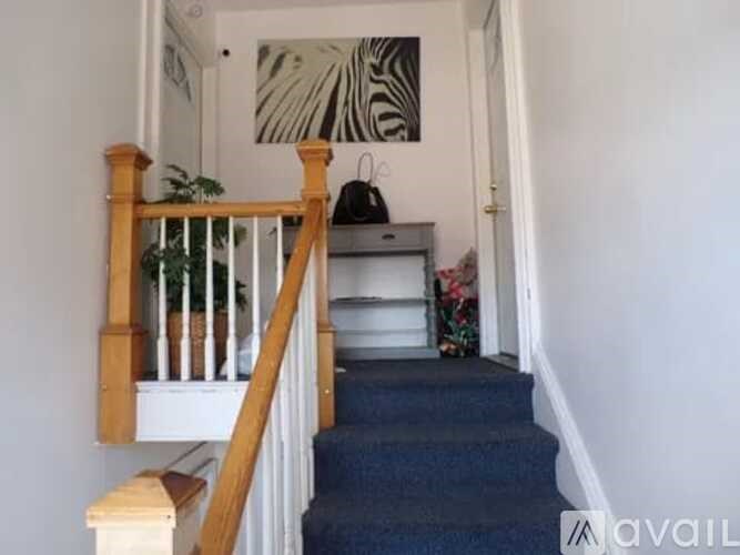 A staircase with a wooden railing and a blue carpeted runner.