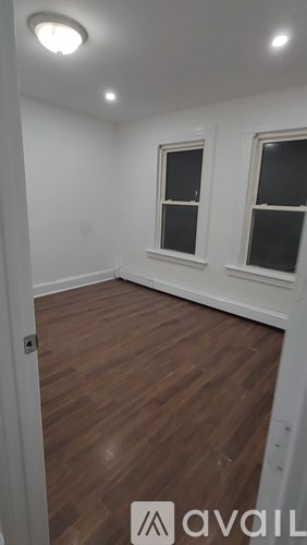 A room with wooden floors and two windows.