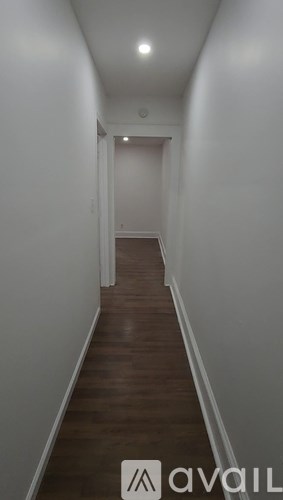 A long hallway with wood floors and white walls.