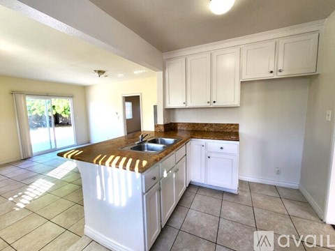A kitchen with white cabinets and a brown countertop.