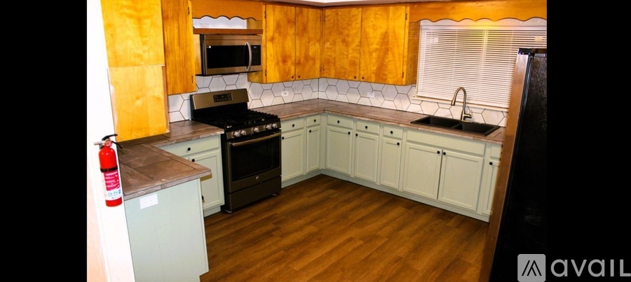 A kitchen with wooden cabinets and a black refrigerator.