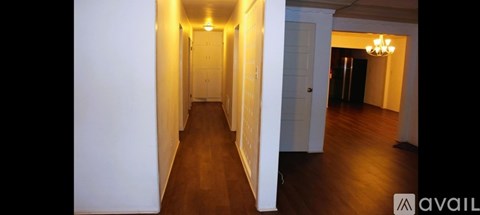 A long hallway with doors on both sides and a chandelier hanging from the ceiling.
