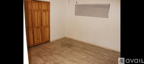 A room with a wooden door and a window with blinds.