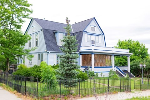 A blue house with white trim and a black fence.