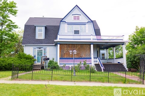 A blue house with a white porch and a black fence.