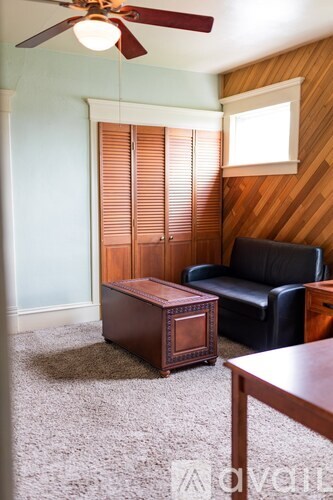 A room with a ceiling fan, a black leather chair, and a wooden coffee table.