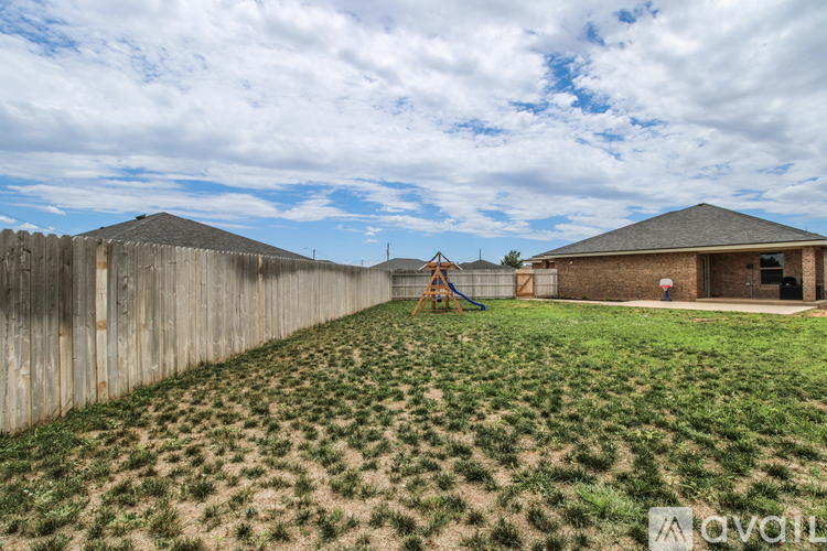 A backyard with a wooden fence and a playground.