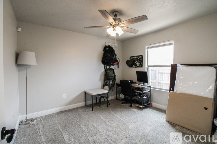 A room with a ceiling fan and a desk with a chair.