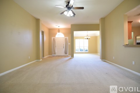 A spacious room with a ceiling fan and carpeted floor.