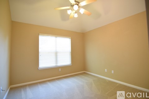 A room with a ceiling fan and a window with blinds.