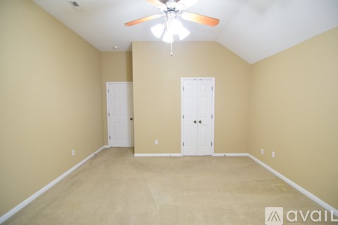 A room with a ceiling fan and two doors.