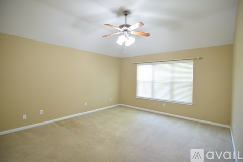 A room with a ceiling fan and a window with blinds.