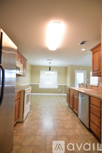 A kitchen with a refrigerator, sink, and cabinets.