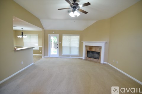 A spacious living room with a fireplace and a ceiling fan.