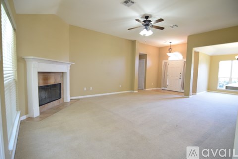 A living room with a fireplace and a ceiling fan.